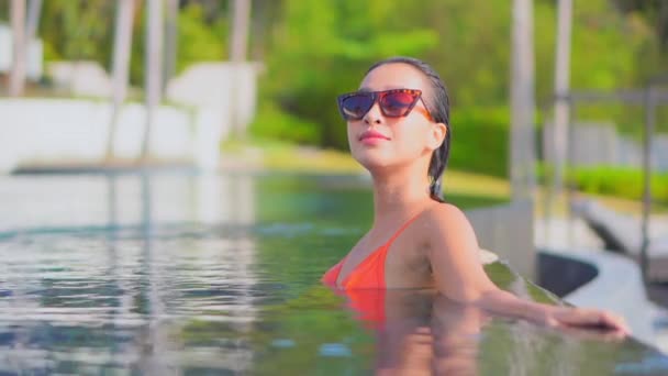 美丽的年轻亚洲女人的镜头 在户外游泳池附近 在海滨度假时 放松地微笑 休闲一下 — 图库视频影像