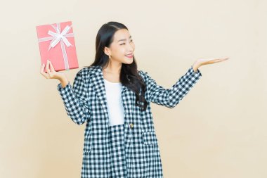 Güzel bir Asyalı kadının portresi. Arka planda kırmızı hediye kutusuyla gülümsüyor.