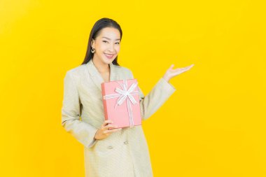 Güzel bir Asyalı kadının portresi. Arka planda kırmızı hediye kutusuyla gülümsüyor.