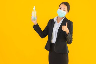 Güzel bir iş kadını portresi. Maske takıyor. Korunmak için alkol jeli kullanıyor.