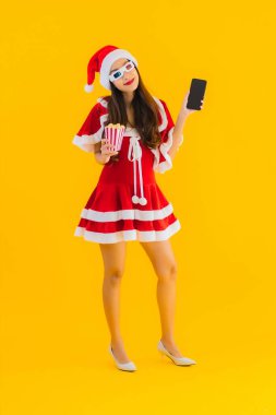 Güzel bir Asyalı kadın portresi patlamış mısır ve 3D gözlüklü noel şapkası takıyor sarı izole edilmiş arka planda film izlemeye hazır.