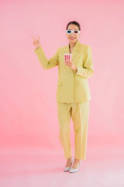 3D gözlüklü ve patlamış mısırlı güzel Asyalı kadın renkli arka planda film izlemeye hazır.