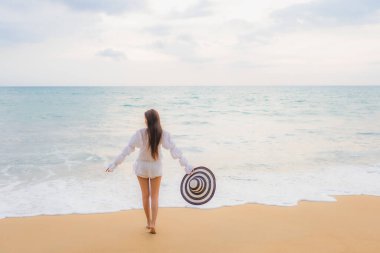 Güzel bir Asyalı kadın portresi deniz kenarında tatil yaparken rahatlar.