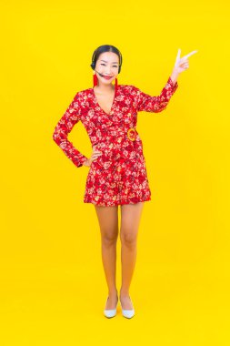 Sarı arka planda, müşteri hizmetleri için kulaklık takan güzel Asyalı kadın portresi.