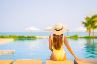 Güzel bir Asyalı kadın portresi. Rahatlayın, gülümseyin. Tatil için oteldeki yüzme havuzunun keyfini çıkarın.
