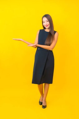 Güzel Asyalı iş kadını portresi. Sarı arka planda hareketli bir gülümseme.