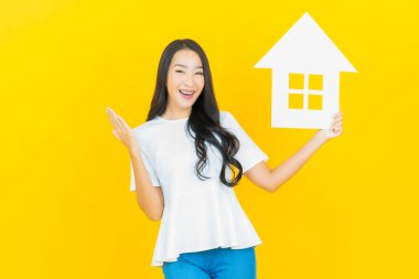 Sarı arka planda ev ya da kağıt tabelalı güzel Asyalı kadın portresi