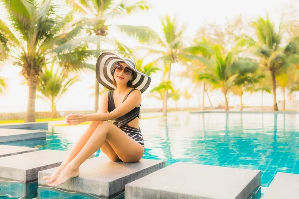 日落时分或日出时分 亚洲年轻貌美的女子带着棕榈树在酒店度假胜地的室外游泳池中悠闲自在地游玩 — 图库照片