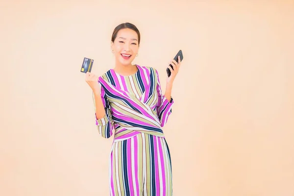 肖像画美しいです若いですアジアの女性とともにスマートフォンやクレジットカードで色隔離された背景 — ストック写真