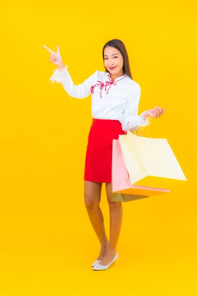 穿着黄色背景的购物袋和信用卡的美丽的年轻亚洲女人的画像 — 图库照片