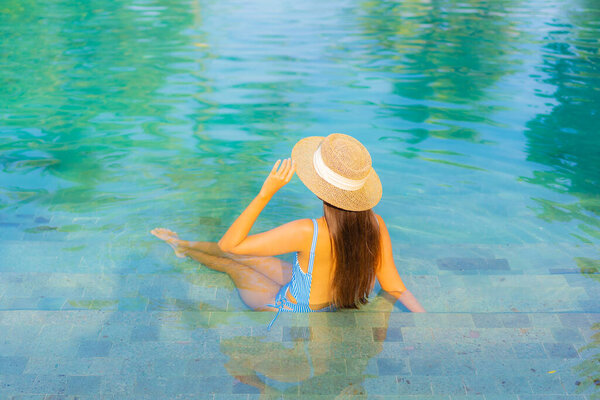 Portrait beautiful young asian woman relax smile enjoy leisure around swimming pool nearly sea beach ocean view for leisure vacation