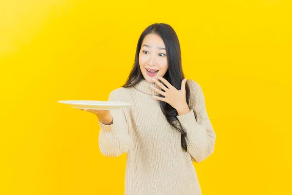 亚洲年轻貌美的女子面带微笑 配上色彩斑斓的空盘子 — 图库照片