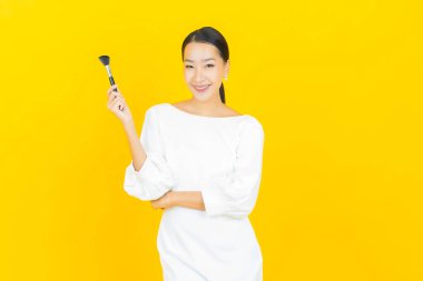 Renk arka planında makyaj fırçası olan güzel Asyalı kadın portresi.