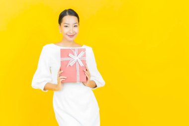 Güzel bir Asyalı kadının portresi. Arka planda kırmızı hediye kutusuyla gülümsüyor.