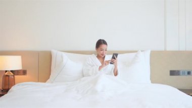 Evde akıllı telefon kullanan Asyalı kadının görüntüleri.