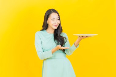 Güzel Asyalı bir kadının portresi. Arka planda boş tabak tabağıyla gülümsüyor.