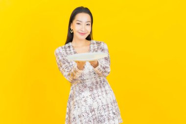 Güzel Asyalı bir kadının portresi. Arka planda boş tabak tabağıyla gülümsüyor.