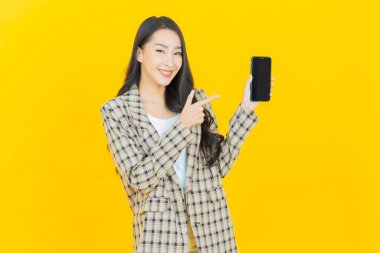 Renkli arka planda akıllı cep telefonuyla güzel Asyalı kadın gülümsemesi