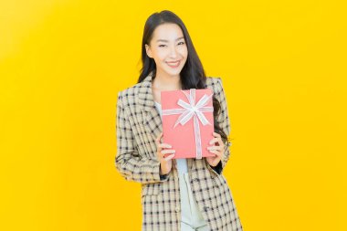 Güzel bir Asyalı kadının portresi. Arka planda kırmızı hediye kutusuyla gülümsüyor.