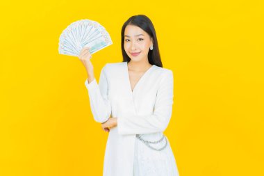 Asyalı güzel bir kadının portresi. Renkli arka planda bol para ve parayla gülümsüyor.