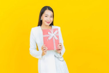 Güzel bir Asyalı kadının portresi. Arka planda kırmızı hediye kutusuyla gülümsüyor.