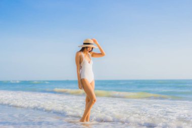 Güzel bir Asyalı kadın portresi. Okyanus sahillerinde mutlu bir gülümseme ve tatil için mavi bir gökyüzü.
