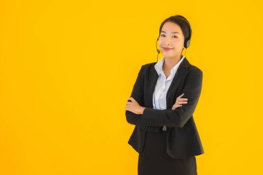 Portre güzel genç Asyalı kadın kulaklık ya da çağrı merkezi için kulaklık ya da tele pazarlama sarı izole arka planda.