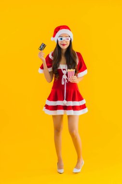 Güzel bir Asyalı kadın portresi patlamış mısır ve 3D gözlüklü noel şapkası takıyor sarı izole edilmiş arka planda film izlemeye hazır.