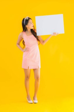 Güzel bir Asyalı kadın portresi sarı izole arkaplanda boş beyaz ilan panosu ve telif alanı gösteriyor.