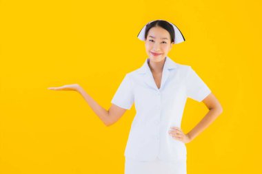 Güzel Asyalı genç Taylandlı hemşirenin portresi klinikteki ve hastanedeki hastalar için sarı izole edilmiş arka planda birçok eylem çalışmasında yer alıyor.