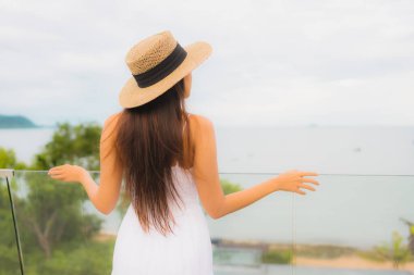 Portriat güzel genç Asyalı kadın deniz manzaralı balkonda mutlu bir gülümseme