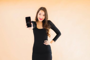 Güzel Asyalı genç bir kadının portresi mutlu bir şekilde gülümsüyor renkli arka planda akıllı cep telefonu kullan