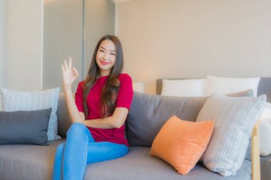 Güzel bir Asyalı kadın portresi. Yatak odasındaki kanepede rahatla. Gülümse.