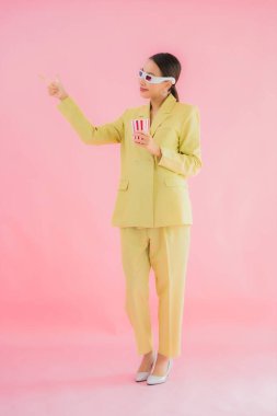 3D gözlüklü ve patlamış mısırlı güzel Asyalı kadın renkli arka planda film izlemeye hazır.