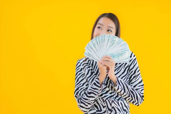 亚洲年轻貌美的女性形象 有很多现金和金钱 背景是黄褐色孤立的 — 图库照片