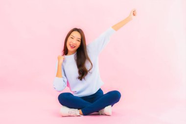 Portrait beautiful young asian woman sit on floor with pink color isolated background