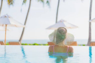Güzel bir Asyalı kadın portresi. Tatil gezisinde deniz manzaralı açık havuz etrafında rahatça yüzebiliyor.
