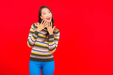 Güzel bir Asyalı kadının portresi. Kırmızı izole edilmiş arka planda hareketli gülümsüyor.