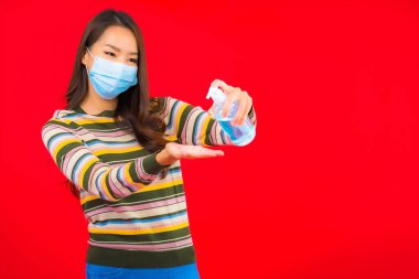 Kırmızı izole edilmiş arka planda alkol jeli güzel Asyalı kadın portresi.