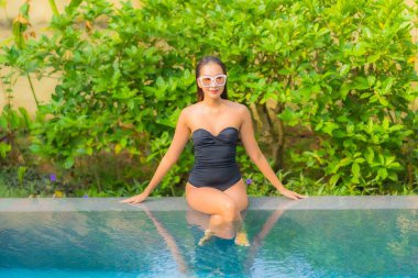 Güzel bir Asyalı kadının portresi tatil için yüzme havuzunda rahatlıyor.