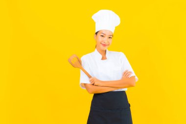 Sarı izole arkaplanda spatulası olan güzel, genç Asyalı şef kadın portresi.