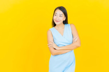 Asyalı güzel bir kadının portresi. Sarı arka planda hareketli gülümsüyor.