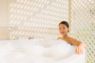 Portre genç Asyalı kadın rahatla spa konsepti için küvette banyo yap.