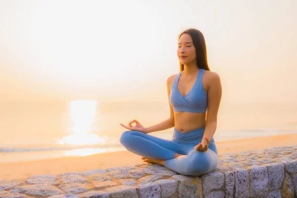 Portrait young asian woman do meditation around sea beach ocean at sunrise for health