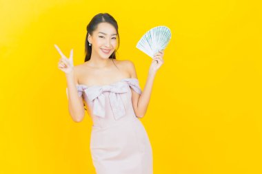 Asyalı güzel bir kadının portresi. Renkli arka planda bol para ve parayla gülümsüyor.