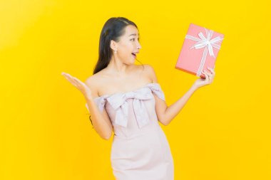 Güzel bir Asyalı kadının portresi. Arka planda kırmızı hediye kutusuyla gülümsüyor.