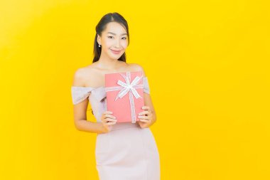 Güzel bir Asyalı kadının portresi. Arka planda kırmızı hediye kutusuyla gülümsüyor.