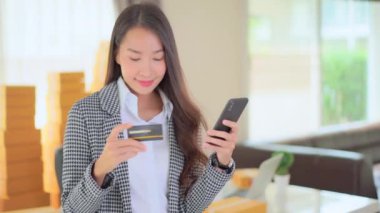 Güzel Asyalı kadının akıllı telefon ve kredi kartıyla e-alışveriş yaptığı görüntüler.
