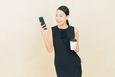 Renkli arka planda akıllı cep telefonuyla güzel Asyalı kadın gülümsemesi