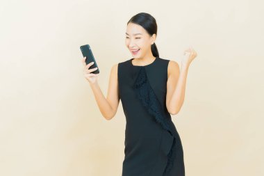 Renkli arka planda akıllı cep telefonuyla güzel Asyalı kadın gülümsemesi